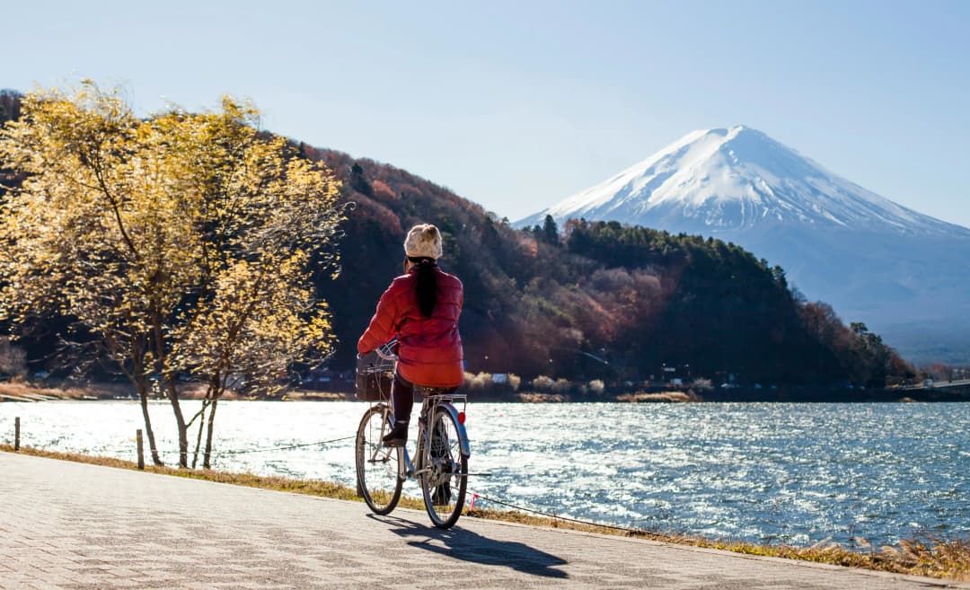 woman riding a bike along the lake near Mount Fuji